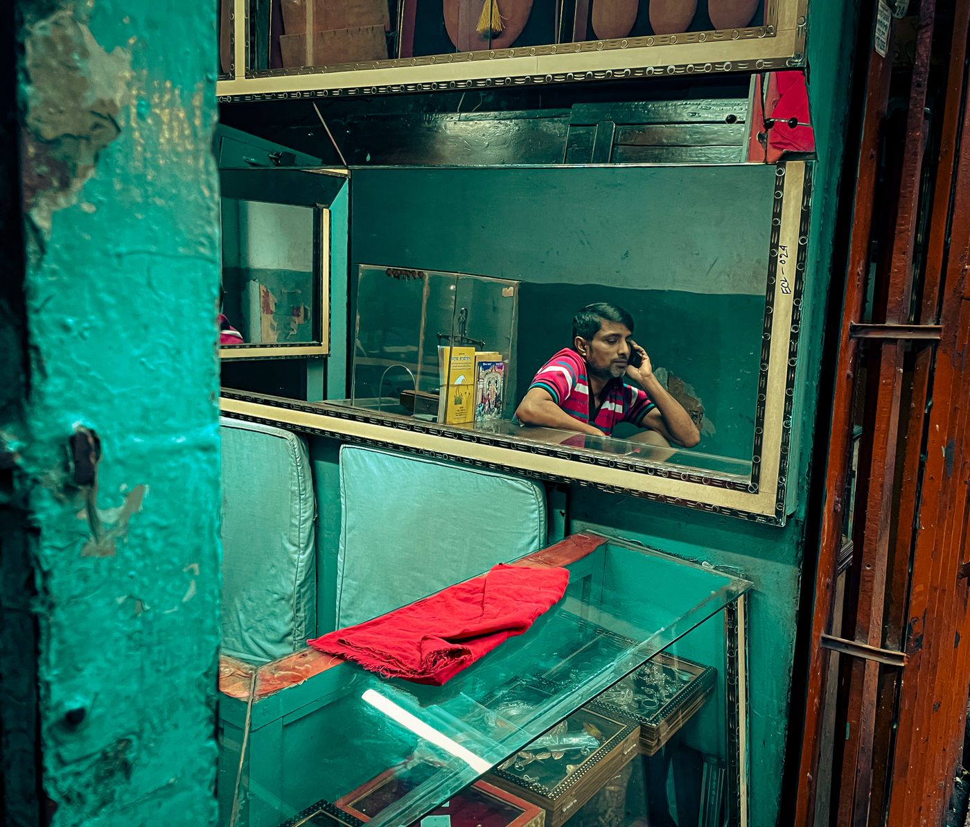 A shopkeeper speaking on a phone inside a Dhaka shop